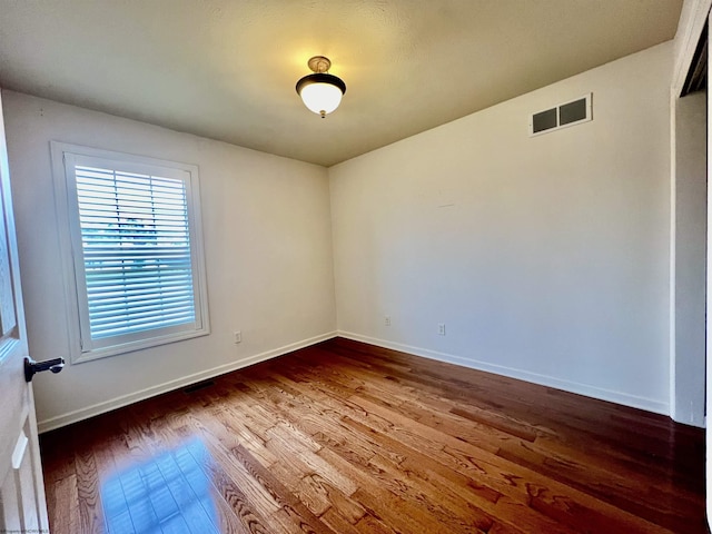 spare room featuring visible vents, baseboards, and wood-type flooring