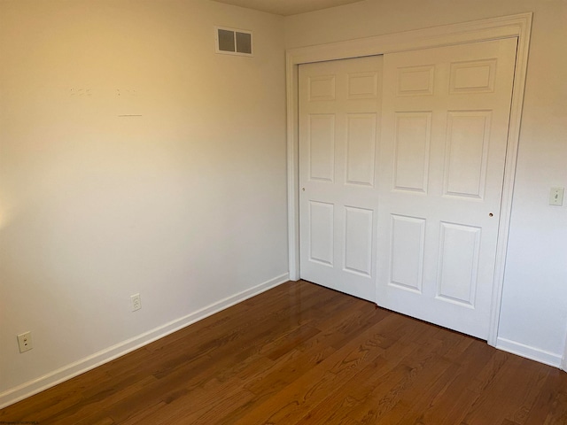 unfurnished bedroom with a closet and dark hardwood / wood-style floors