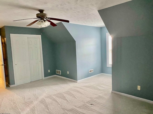 additional living space with ceiling fan, a textured ceiling, lofted ceiling, and light carpet