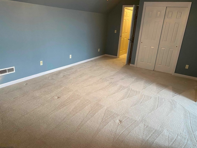 unfurnished bedroom featuring light carpet, vaulted ceiling, and a closet