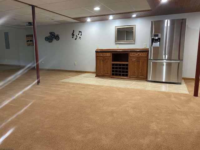 interior space featuring light colored carpet, stainless steel refrigerator with ice dispenser, a drop ceiling, and electric panel