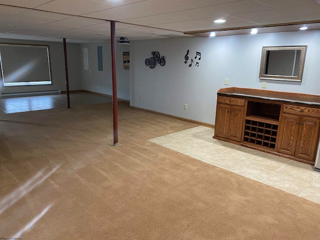 basement featuring a drop ceiling, light colored carpet, and electric panel