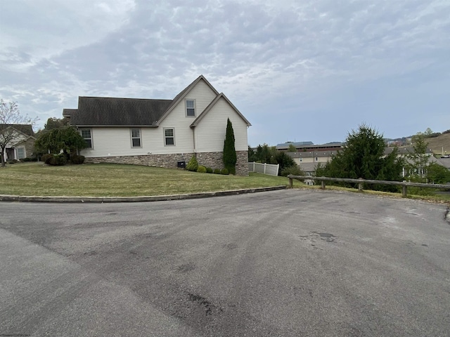 view of side of property with a lawn, fence, and stone siding