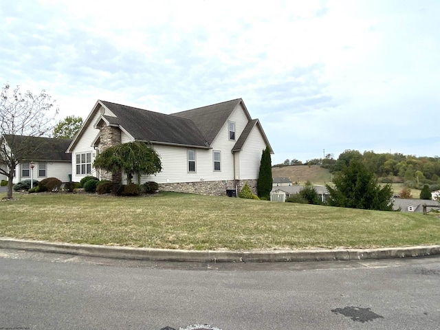 view of side of home featuring a yard and a shingled roof