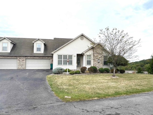 view of front facade featuring a front yard, driveway, stone siding, and a garage