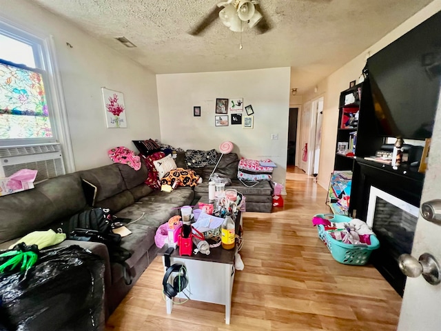 living room featuring a textured ceiling, cooling unit, ceiling fan, and light hardwood / wood-style flooring