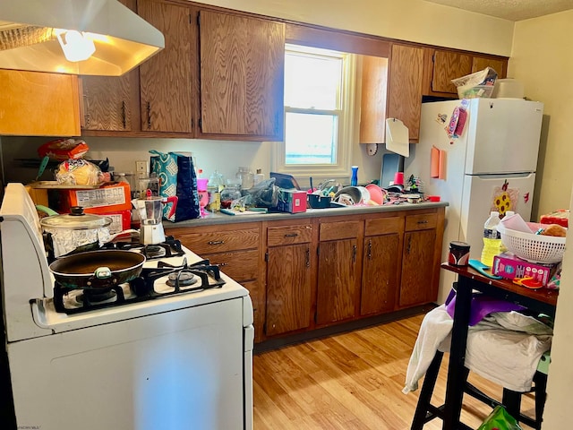 kitchen with white appliances, light wood-type flooring, and extractor fan