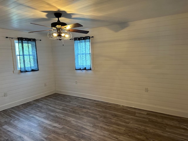 spare room with wood walls, ceiling fan, and dark wood-type flooring