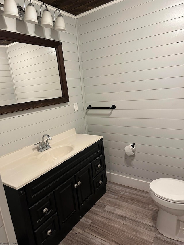 bathroom featuring wood walls, vanity, toilet, and hardwood / wood-style floors