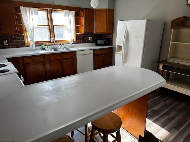 kitchen featuring tasteful backsplash, sink, kitchen peninsula, white appliances, and dark hardwood / wood-style flooring