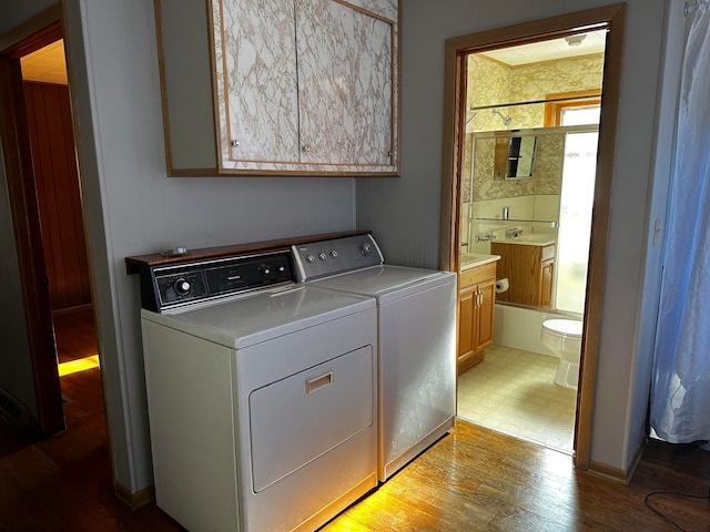 clothes washing area featuring light hardwood / wood-style flooring, wood walls, cabinets, and washer and dryer