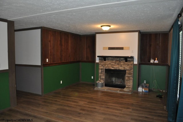 unfurnished living room with a stone fireplace, a textured ceiling, and dark wood-type flooring