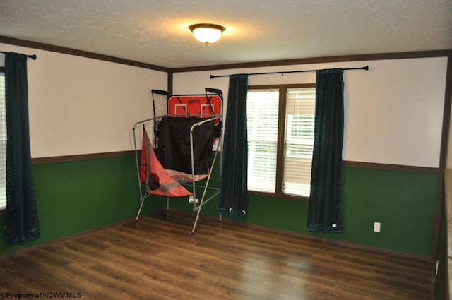 unfurnished room with ornamental molding, a textured ceiling, and hardwood / wood-style floors