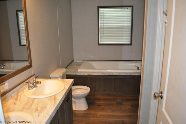 bathroom featuring vanity, hardwood / wood-style floors, toilet, and a bath