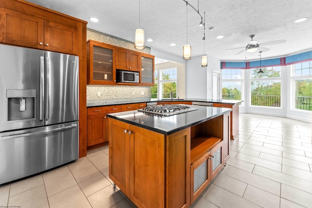 kitchen with stainless steel appliances, ceiling fan, a kitchen island, and a textured ceiling