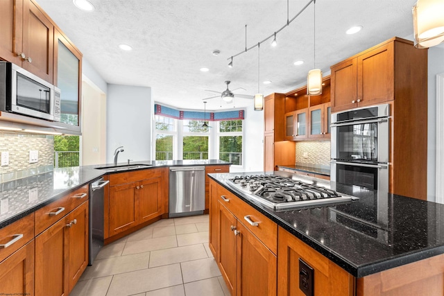 kitchen with dark stone counters, appliances with stainless steel finishes, and plenty of natural light