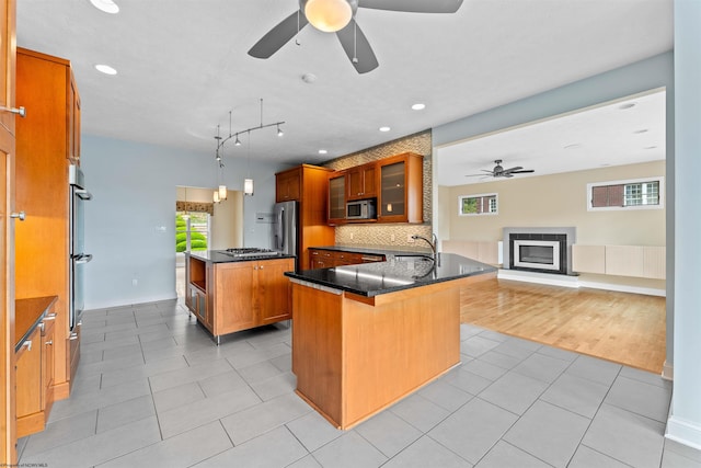 kitchen with appliances with stainless steel finishes, a breakfast bar, pendant lighting, ceiling fan, and a center island with sink