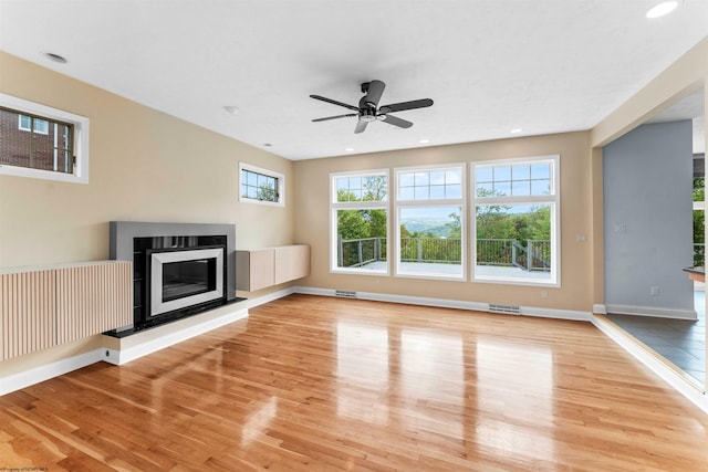 unfurnished living room featuring radiator heating unit, ceiling fan, and light hardwood / wood-style flooring