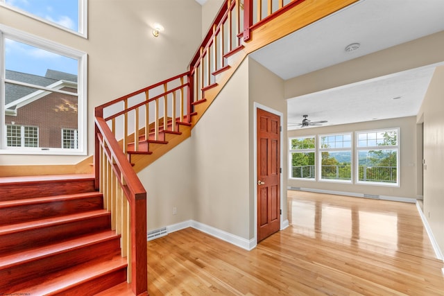 stairs featuring ceiling fan and hardwood / wood-style flooring