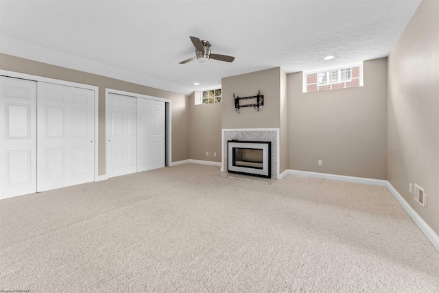 unfurnished living room featuring a wealth of natural light, ceiling fan, and carpet flooring