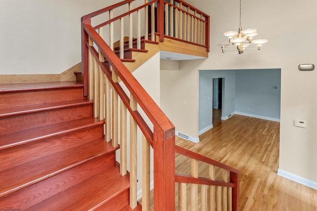 stairway with hardwood / wood-style floors and a chandelier