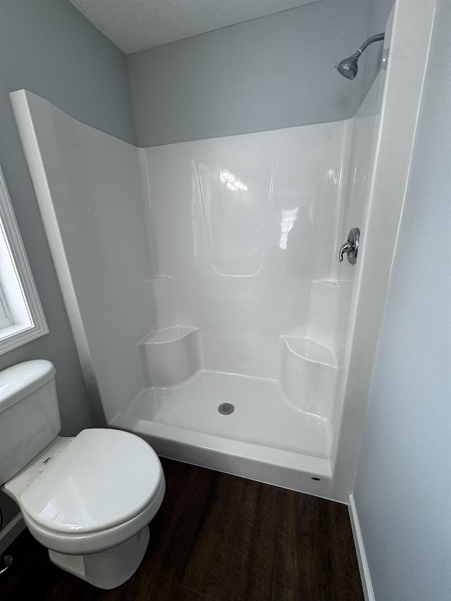 bathroom featuring toilet, hardwood / wood-style flooring, a textured ceiling, and walk in shower