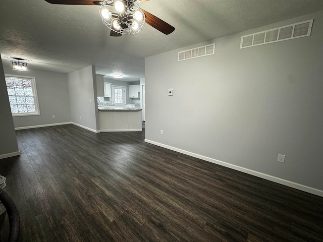 unfurnished living room featuring a textured ceiling and dark hardwood / wood-style flooring