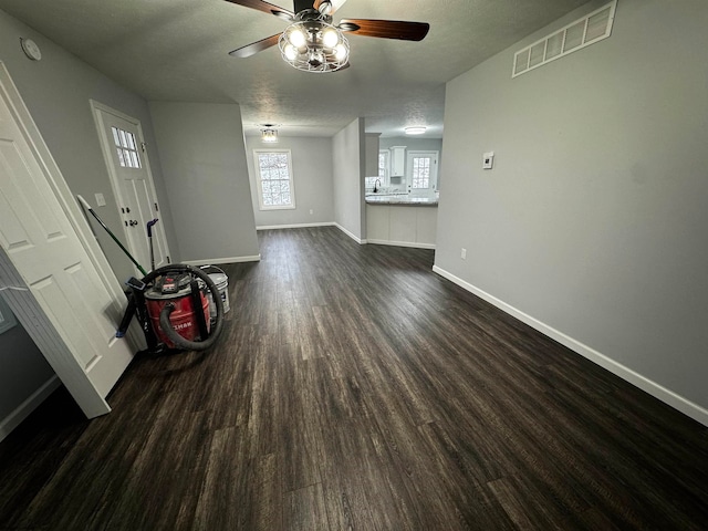 unfurnished living room with a textured ceiling, ceiling fan, and dark hardwood / wood-style flooring