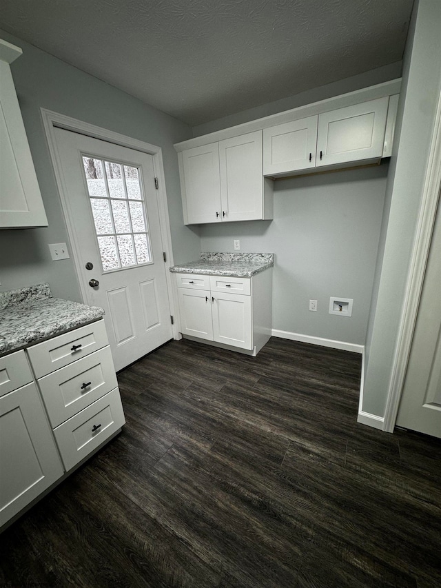 kitchen with light stone countertops, white cabinets, and dark hardwood / wood-style floors