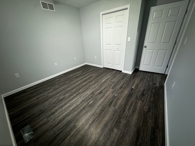 unfurnished bedroom featuring dark wood-type flooring and a closet