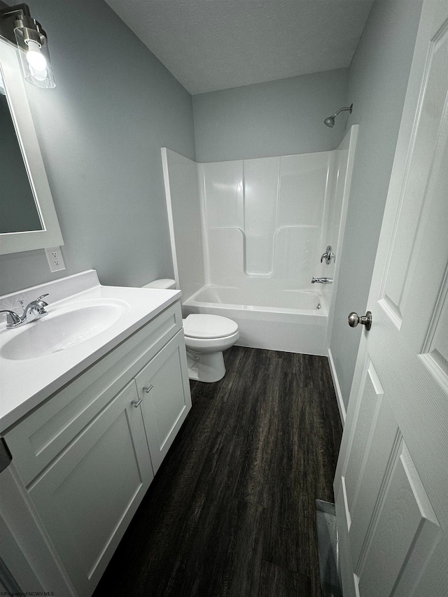 full bathroom with shower / washtub combination, toilet, vanity, hardwood / wood-style flooring, and a textured ceiling