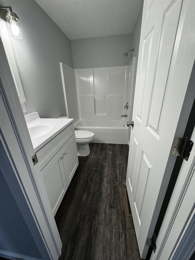 full bathroom with toilet, a textured ceiling, hardwood / wood-style floors, shower / tub combination, and vanity