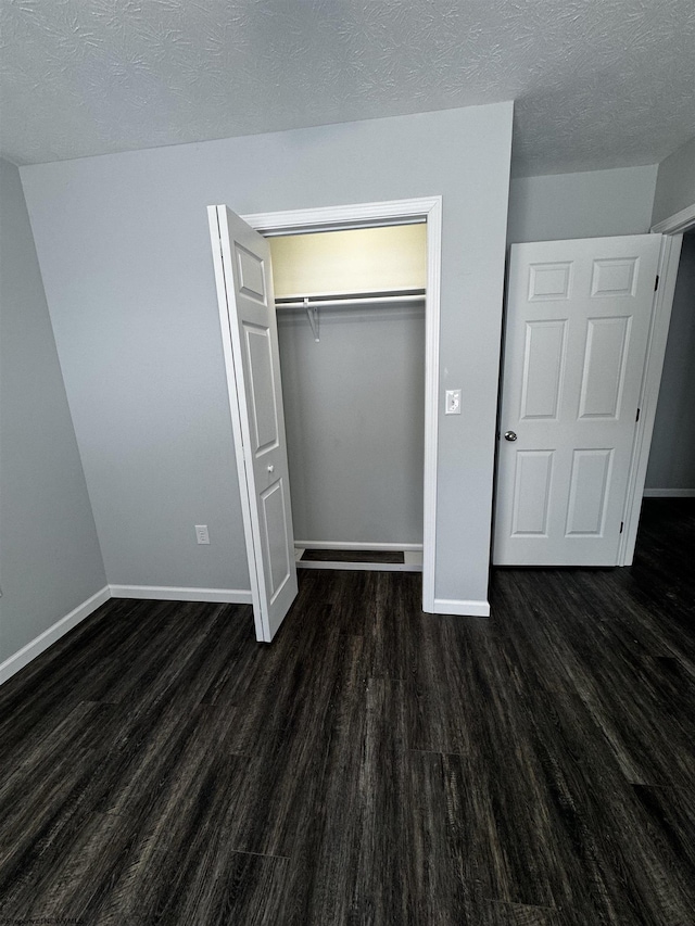 unfurnished bedroom with a textured ceiling, a closet, and dark hardwood / wood-style flooring