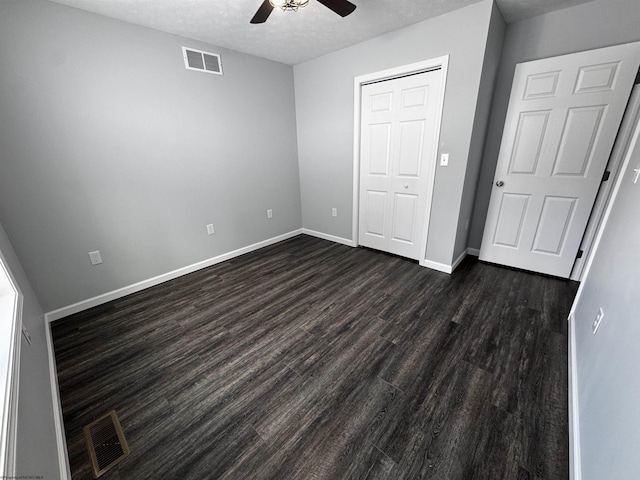 unfurnished bedroom with dark wood-type flooring, a textured ceiling, ceiling fan, and a closet