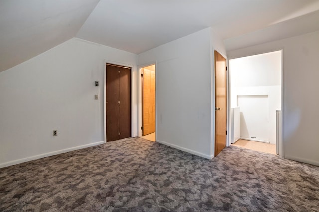 unfurnished bedroom featuring a closet, vaulted ceiling, and carpet