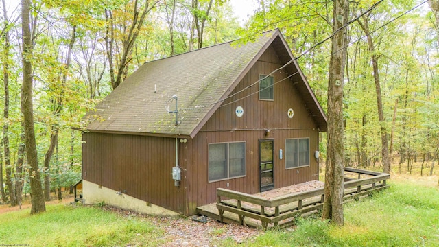 rear view of property with a wooden deck and a lawn