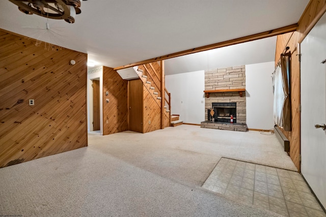 unfurnished living room with light carpet, a stone fireplace, and wooden walls