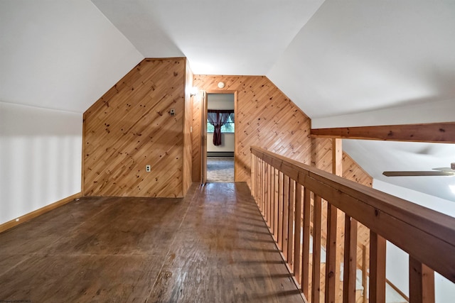 interior space featuring dark hardwood / wood-style floors, wood walls, vaulted ceiling, a baseboard radiator, and ceiling fan