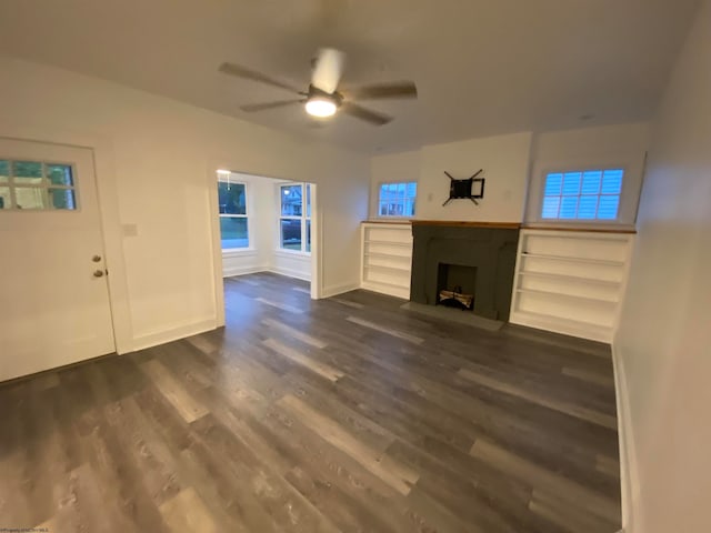 unfurnished living room with dark hardwood / wood-style floors and ceiling fan