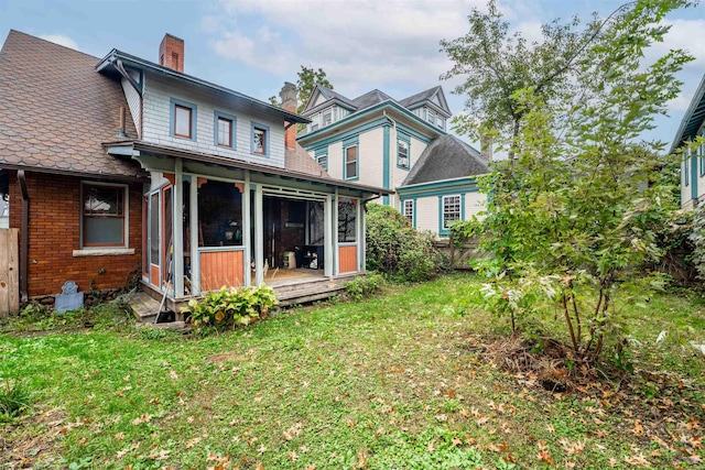 rear view of property featuring a sunroom and a yard