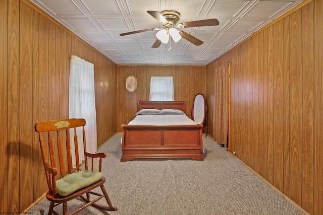 carpeted bedroom featuring wooden walls and ceiling fan