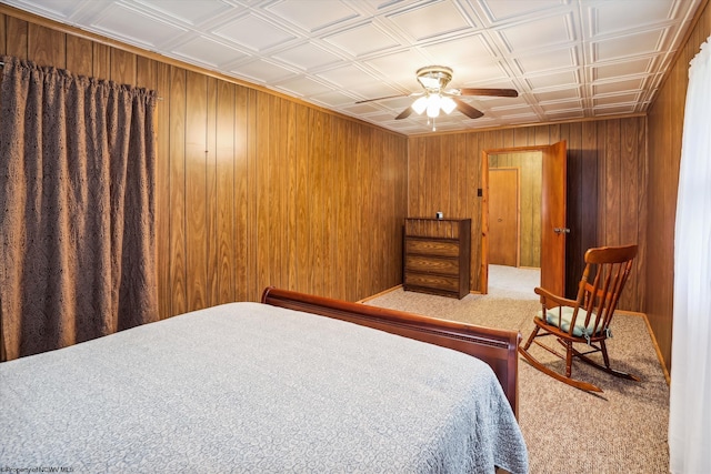 bedroom with ceiling fan, wood walls, and carpet