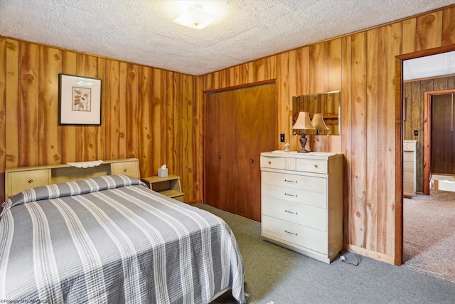 carpeted bedroom featuring a textured ceiling, wooden walls, and a closet