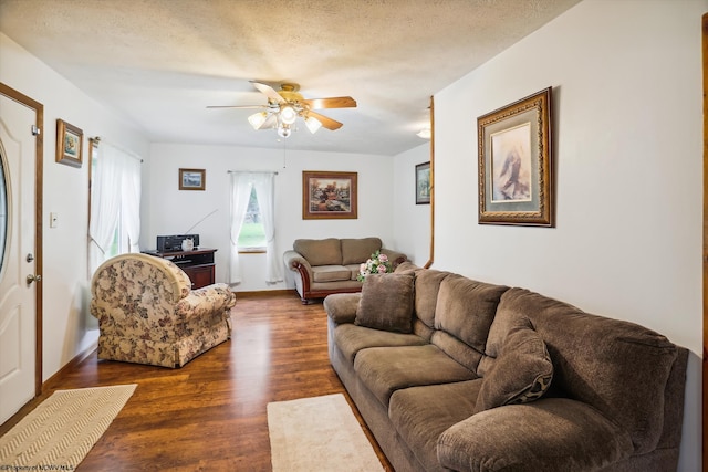 living room featuring ceiling fan, dark hardwood / wood-style floors, and a textured ceiling