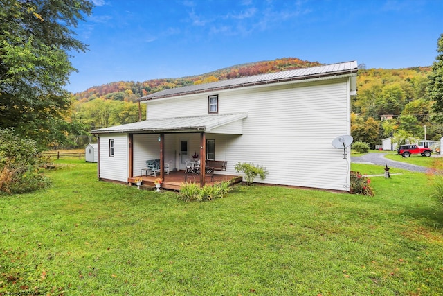 back of property featuring a yard and a deck with mountain view