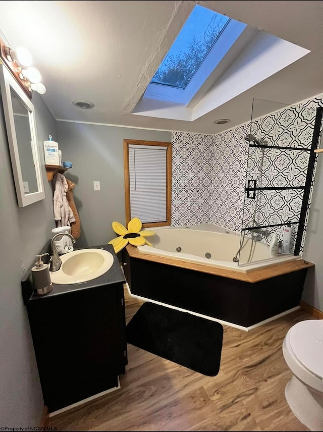 bathroom with vanity, a skylight, hardwood / wood-style flooring, a bath, and toilet