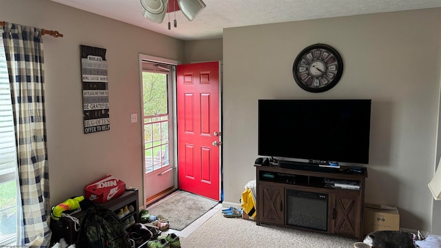 foyer entrance with light carpet, ceiling fan, and a textured ceiling