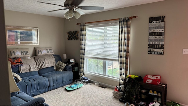 living room with a textured ceiling, carpet floors, visible vents, a ceiling fan, and baseboards