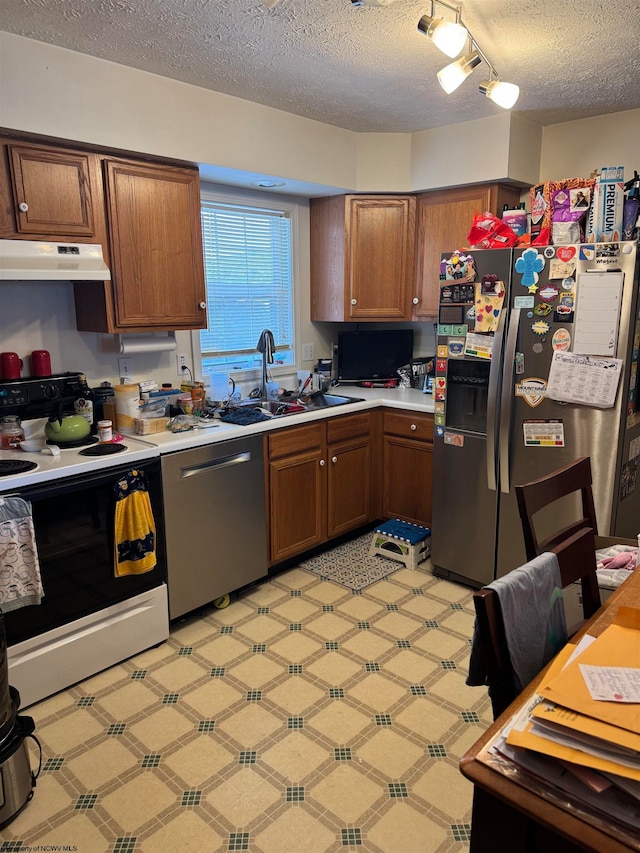 kitchen with light floors, stainless steel appliances, light countertops, a sink, and under cabinet range hood