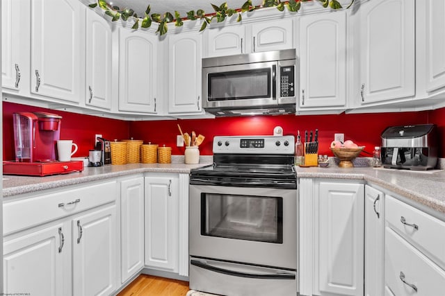 kitchen featuring appliances with stainless steel finishes, light wood-type flooring, and white cabinets